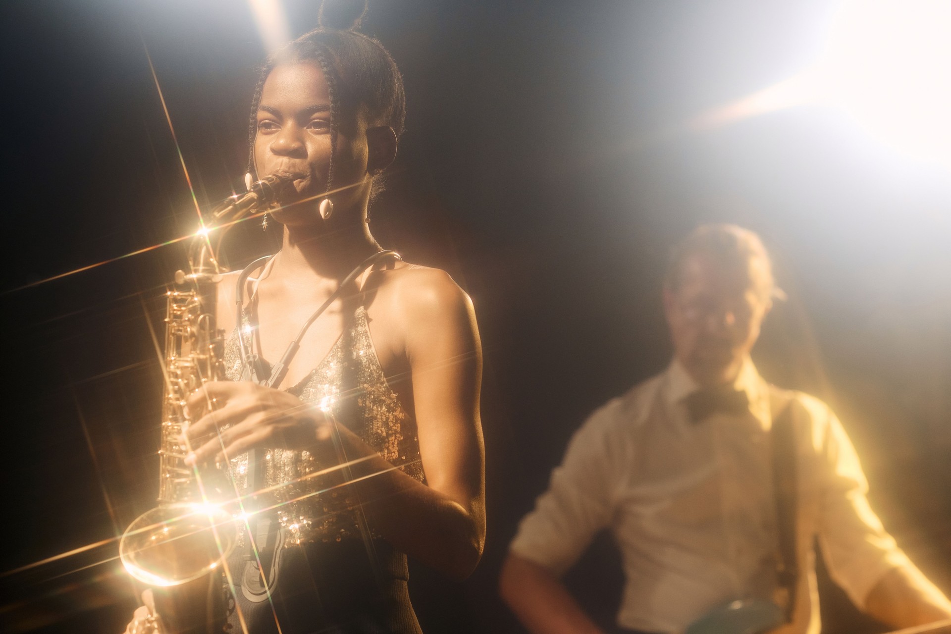 Black Woman Playing Saxophone with Band on Stage in Nightclub